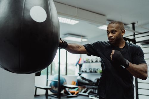 Free A dedicated African American man practices punching on a heavy bag in a gym setting. Stock Photo