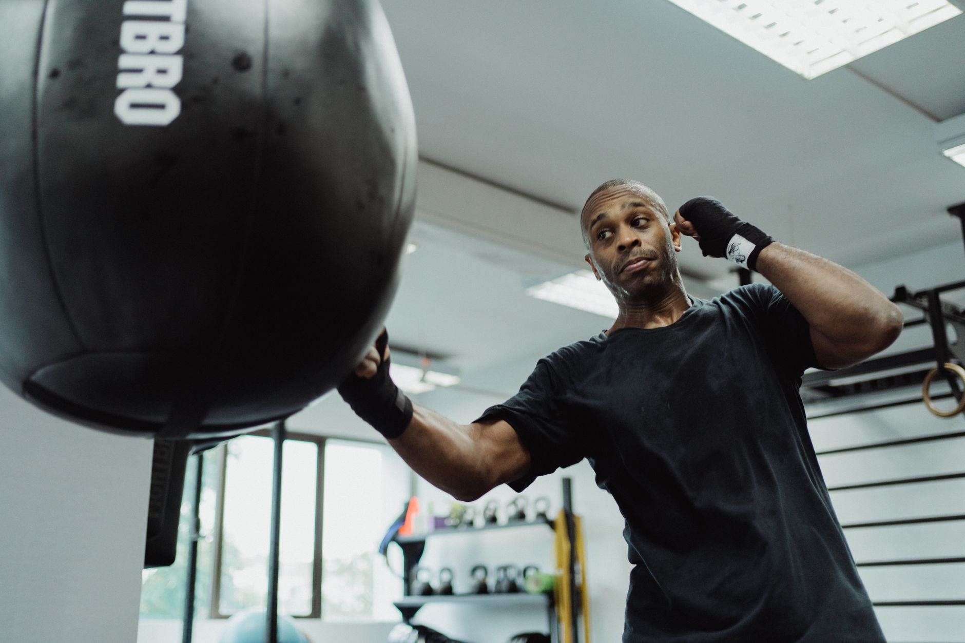African American male boxer in a gym focusing on training with a punching bag.