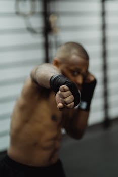 A determined boxer with bandaged hands practicing in a gym, showcasing power and focus.