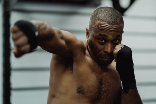 Free Intense boxer throwing a punch during an indoor training session, showcasing strength and determination. Stock Photo