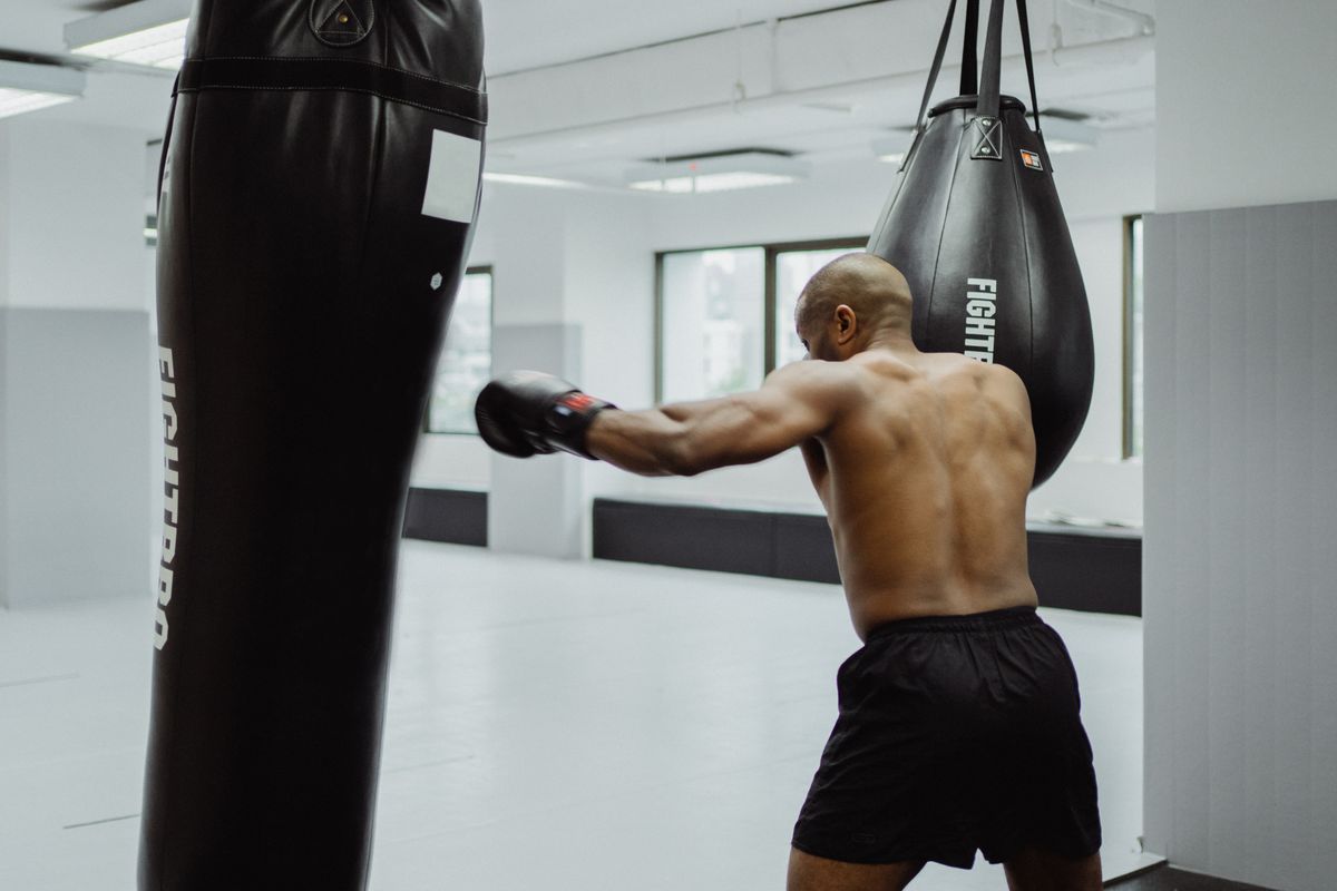 Athlete practicing boxing with a heavy bag in a gym