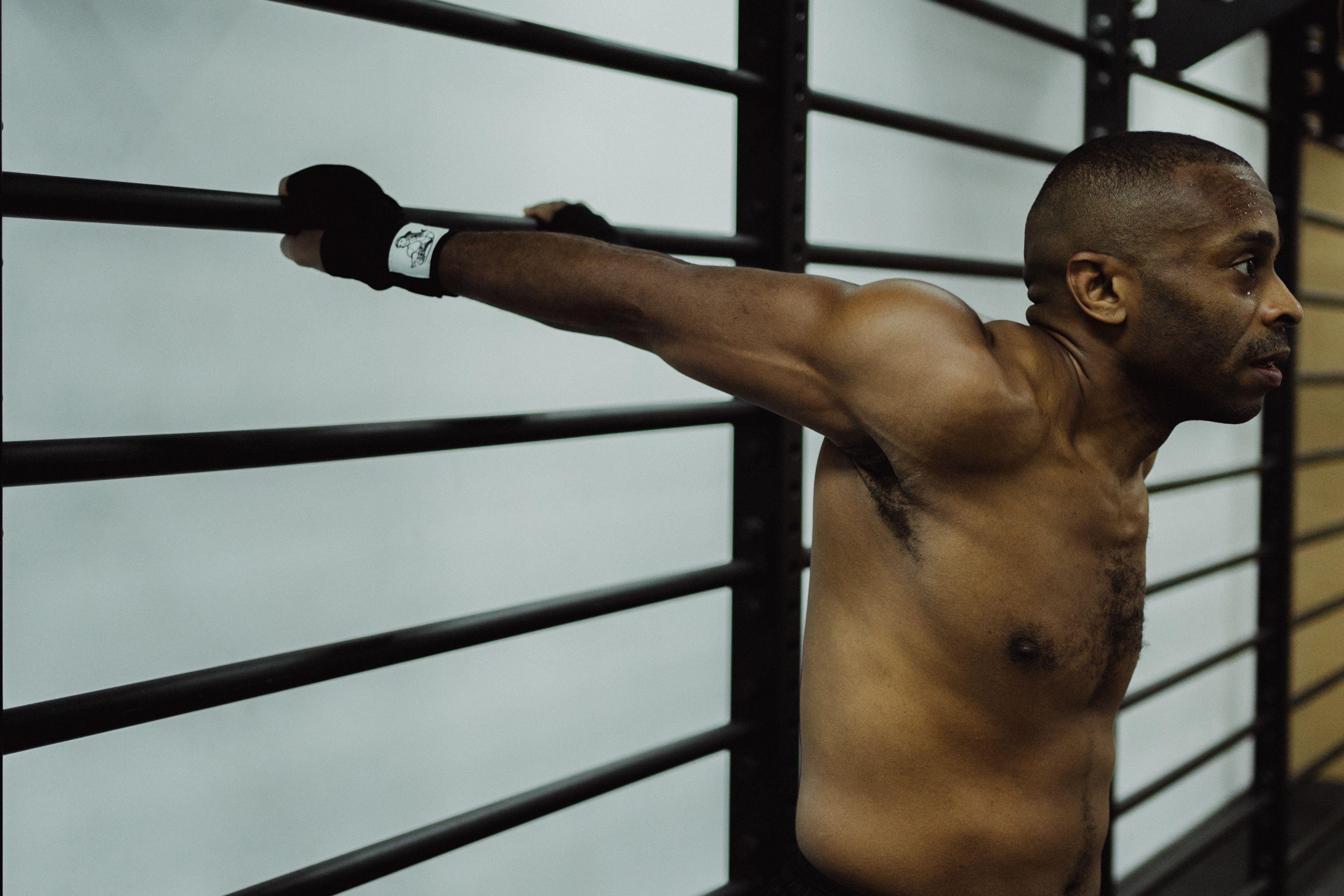 African American man doing strength exercise with metal bars indoors.