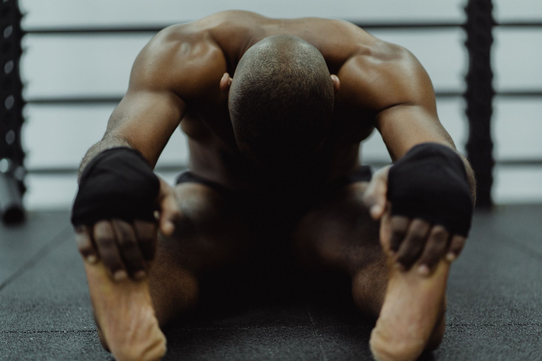 A man sitting on the floor of a gym, stretching to improve fitness and flexibility.