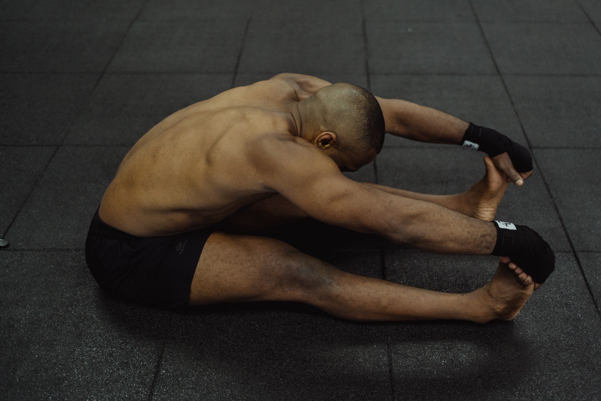 Athlete stretching on a gym floor during recovery work