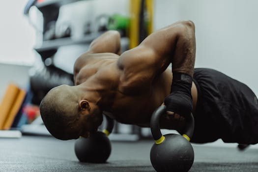 A shirtless man engages in intense kettlebell push-ups for strength and fitness.