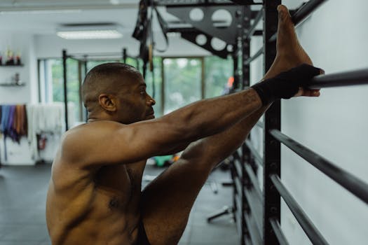 African American man warming up while stretching on wall bars indoors.