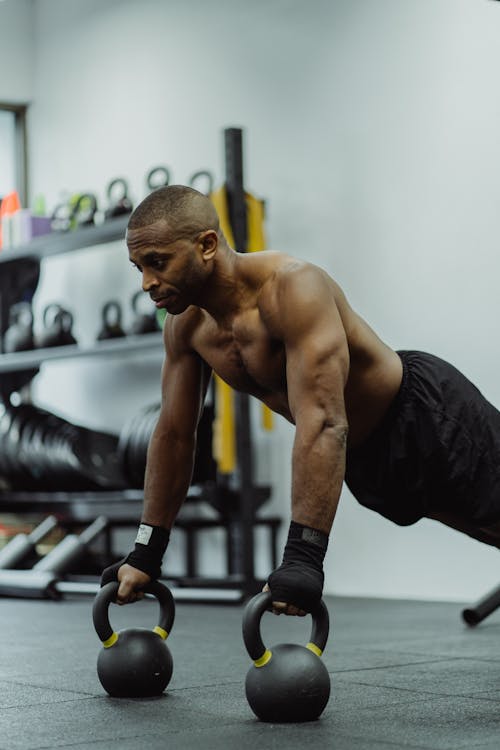 Free Man Using Kettle Bell While Working Out  Stock Photo