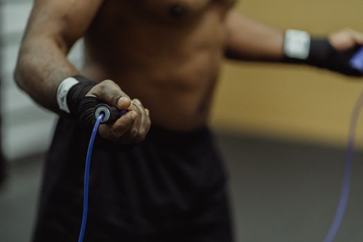 Focused shot of a man's hand holding a jump rope, emphasizing fitness and training.