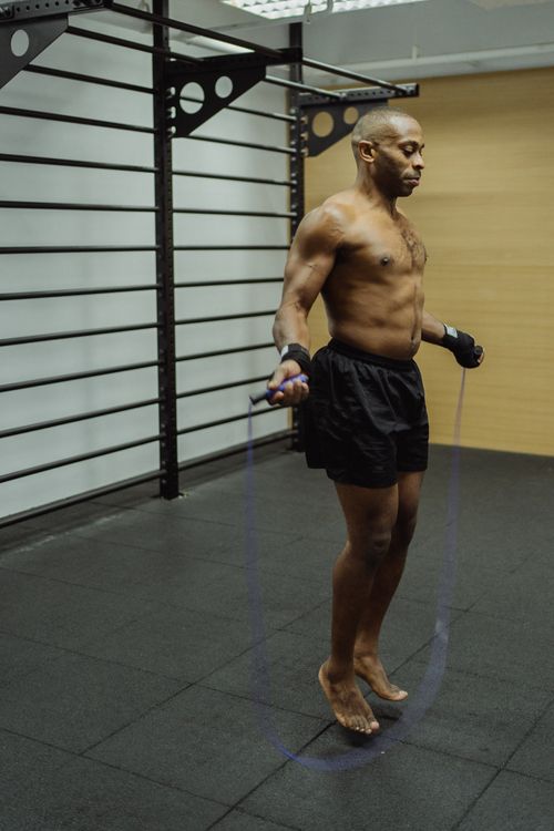 Free Fit African American man exercising with jump rope indoors, showcasing strength and fitness. Stock Photo