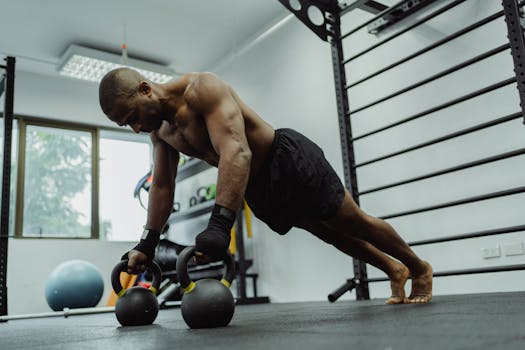 Muscular man performing push-ups with kettlebells in a gym setting, showcasing strength and fitness.