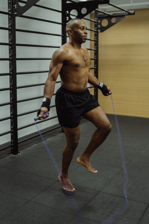 Free Muscular African American man jumping rope in a gym setting, focused on fitness. Stock Photo