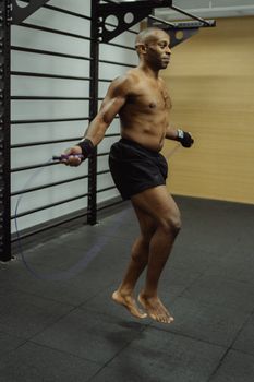 African American man exercising with a jump rope in a gym. High-energy fitness routine.