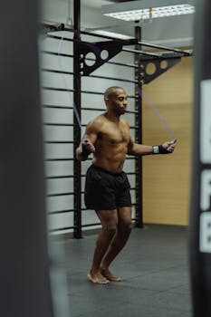 Athletic man jumping rope indoors, showcasing fitness and strength.