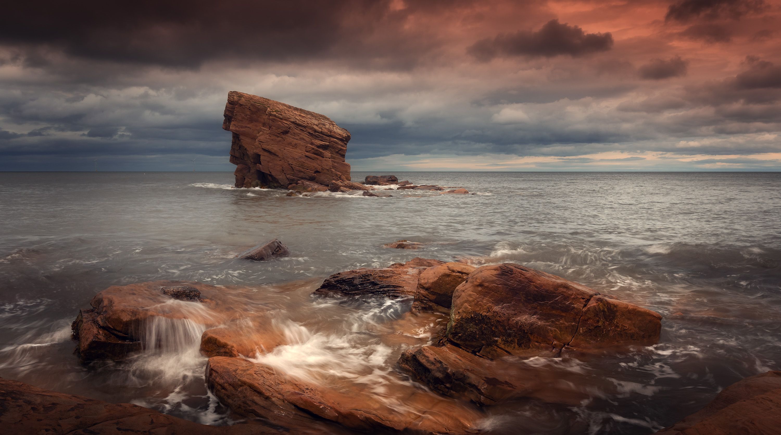 Captivating seascape capturing waves crashing against dramatic rocks under a moody sky.