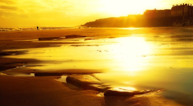 Capture the warmth of a breathtaking sunset on a serene beach with reflections on the sand.