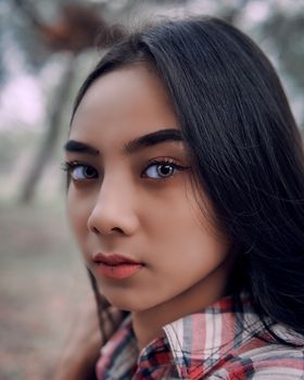 一位留着深色长发的年轻女子在户外的特写肖像