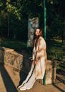 Woman in Beige Robe Standing on Brown Concrete Pathway