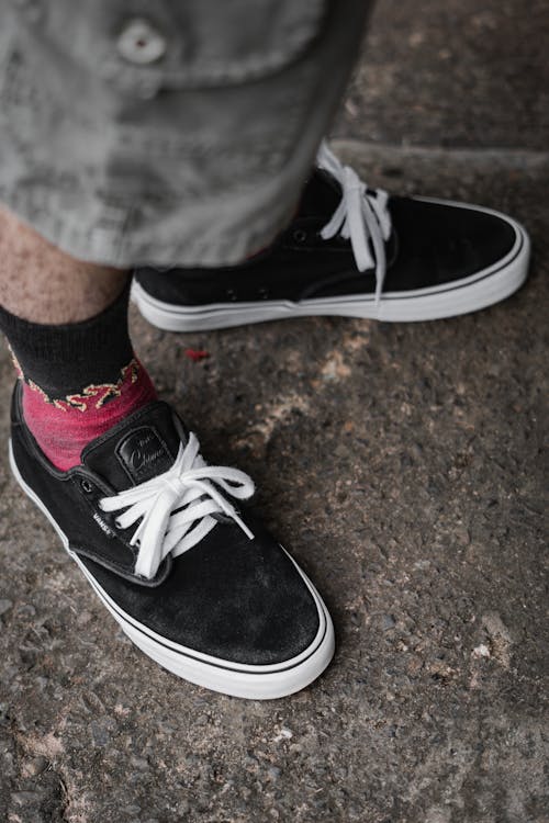Person Wearing Black Sneakers Standing on Concrete Floor