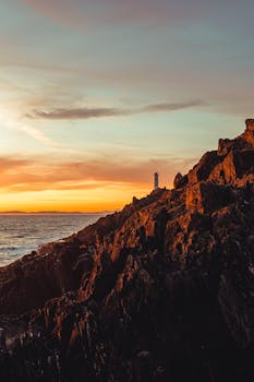 Scenery view of bristly mount near rippled sea under bright cloudy sky at sunset