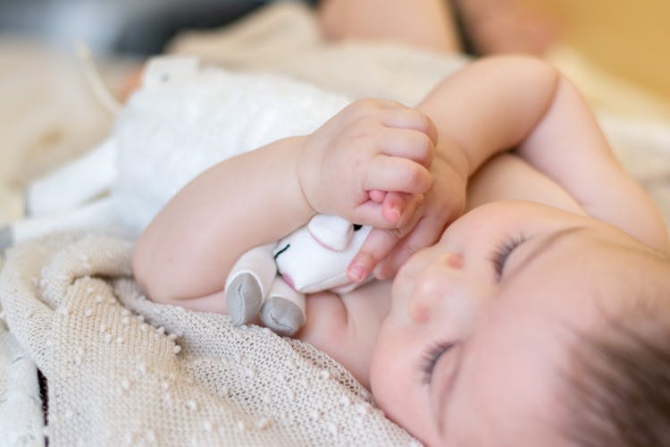 Baby Lying On A Blanket Holding A Toy