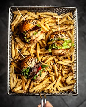 Overhead view of juicy burgers and crispy french fries in a basket, perfect for fast food lovers.