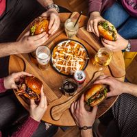 Overhead view of hands reaching across a laden table, photo by Askar Abayev on Pexels