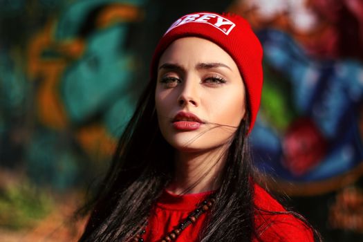 Young attentive female with red lips in trendy wear looking at camera on street