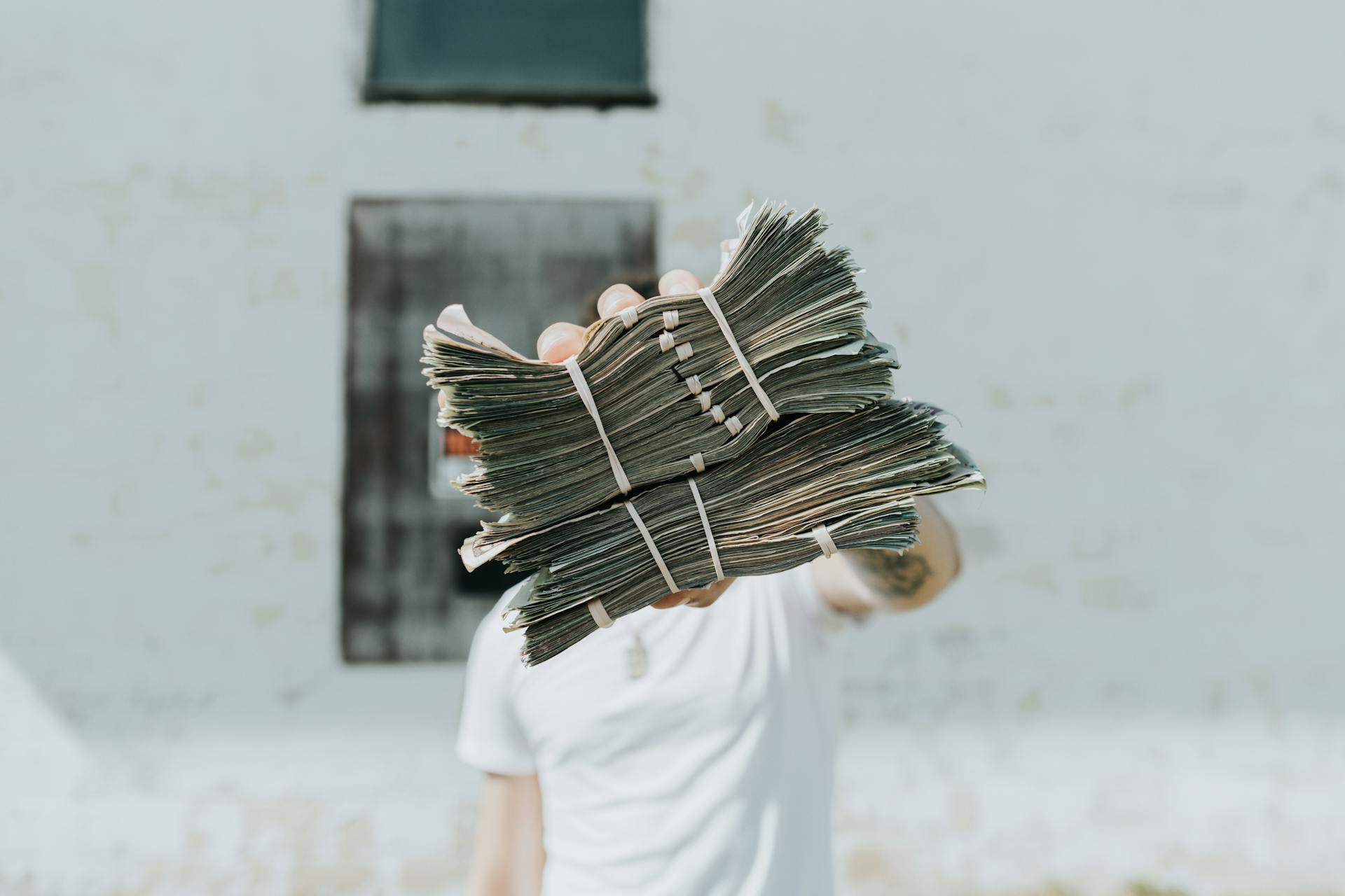 A person holding a large stack of cash outdoors, showcasing wealth and abundance.