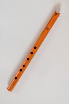 Natural wooden flute displayed on a gray background, showcasing traditional craftsmanship.