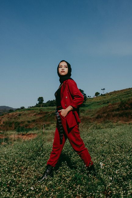 Fashionable Asian woman in a red coat posing in scenic Bandung, Indonesia.