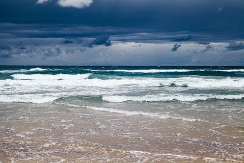 Ocean Waves Crashing on Shore Under Dark Clouds