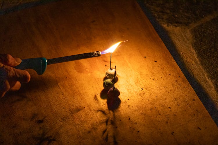 Person Lighting A Firecracker On A Wooden Table 