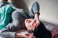 一名女子躺在室内的床上，显得放松又疲倦