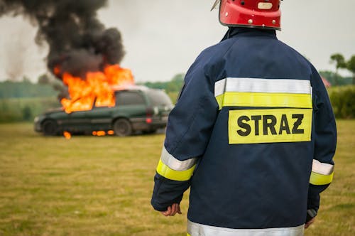 бесплатная Пожарный наблюдает за пылающим автомобилем Стоковое фото