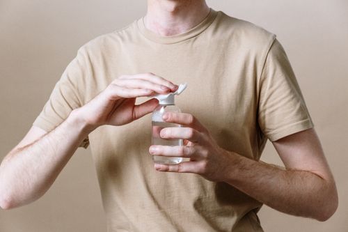 Free Adult male opening a bottle of micellar water, representing a skincare routine. Stock Photo