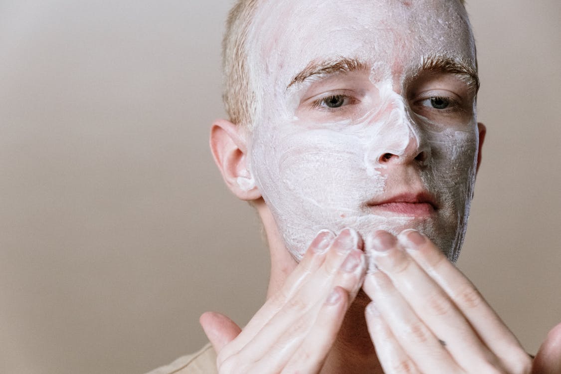 Acne dos and donts: Man washing his face with a non abrasive cleanser