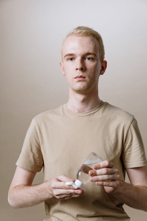 Man in Beige Crew Neck T-shirt Holding Clear Drinking Glass