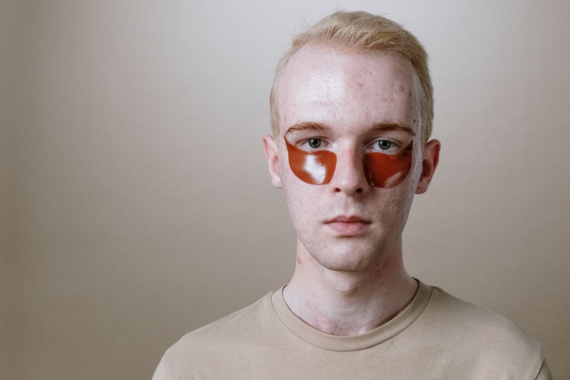 Portrait of a young man using skincare eye patches for a fresh look.