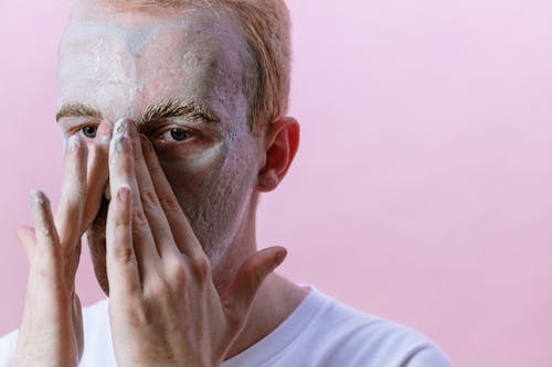 Man in White Crew Neck Shirt Covering His Face With His Hand