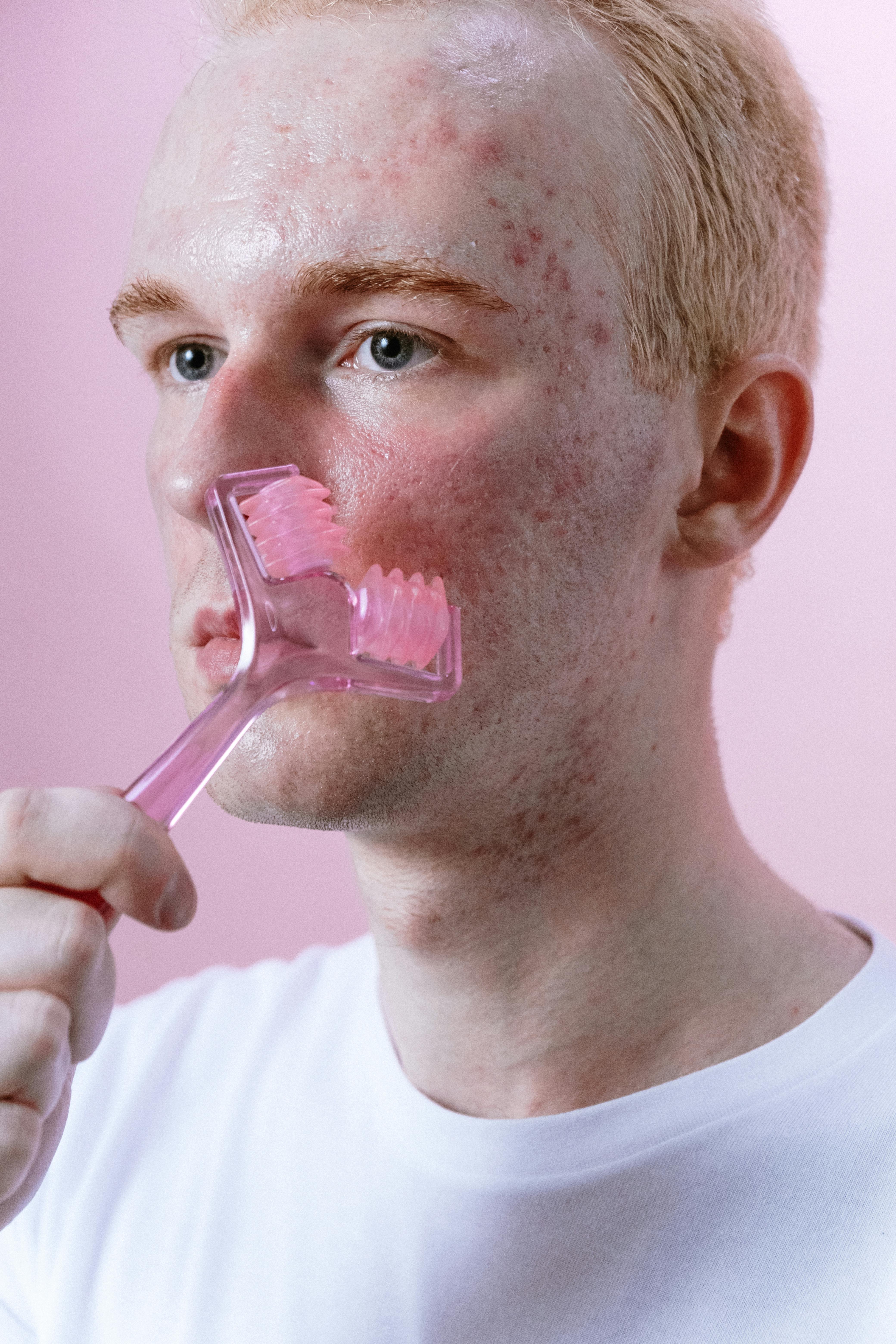 man in white crew neck shirt holding pink lollipop