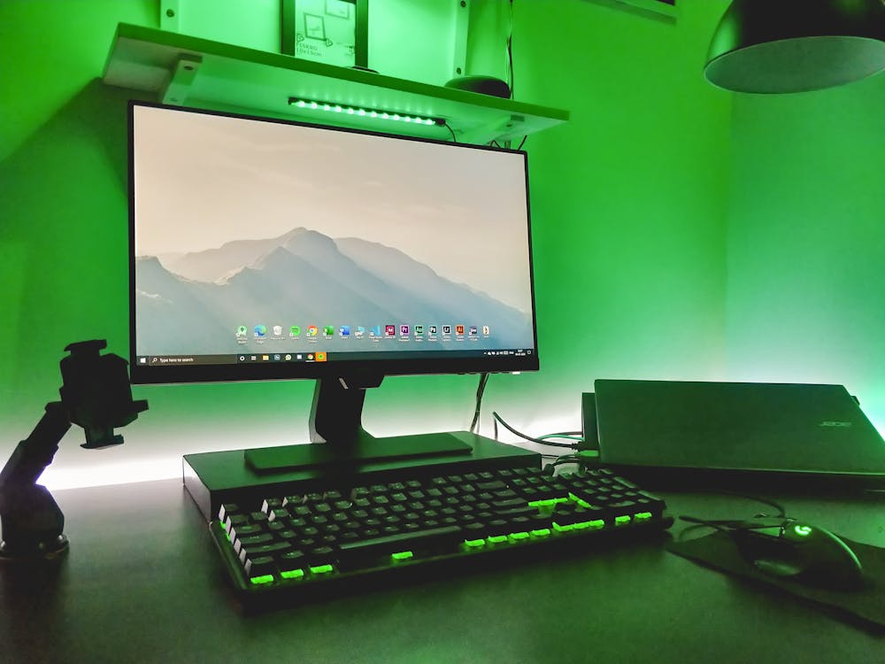 A Desktop Computer Turned On With Green Light Reflection In A Room