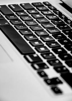 Monochrome close-up of a laptop's keyboard with a focus on keys and depth of field.
