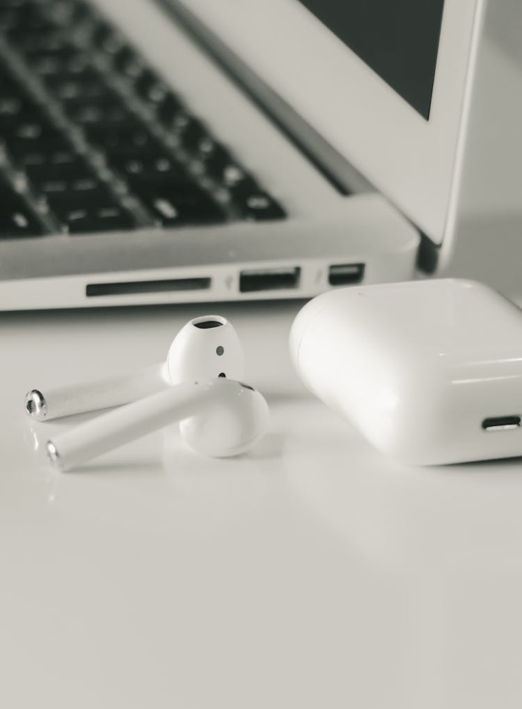 Apple Airpods Beside A Macbook Pro