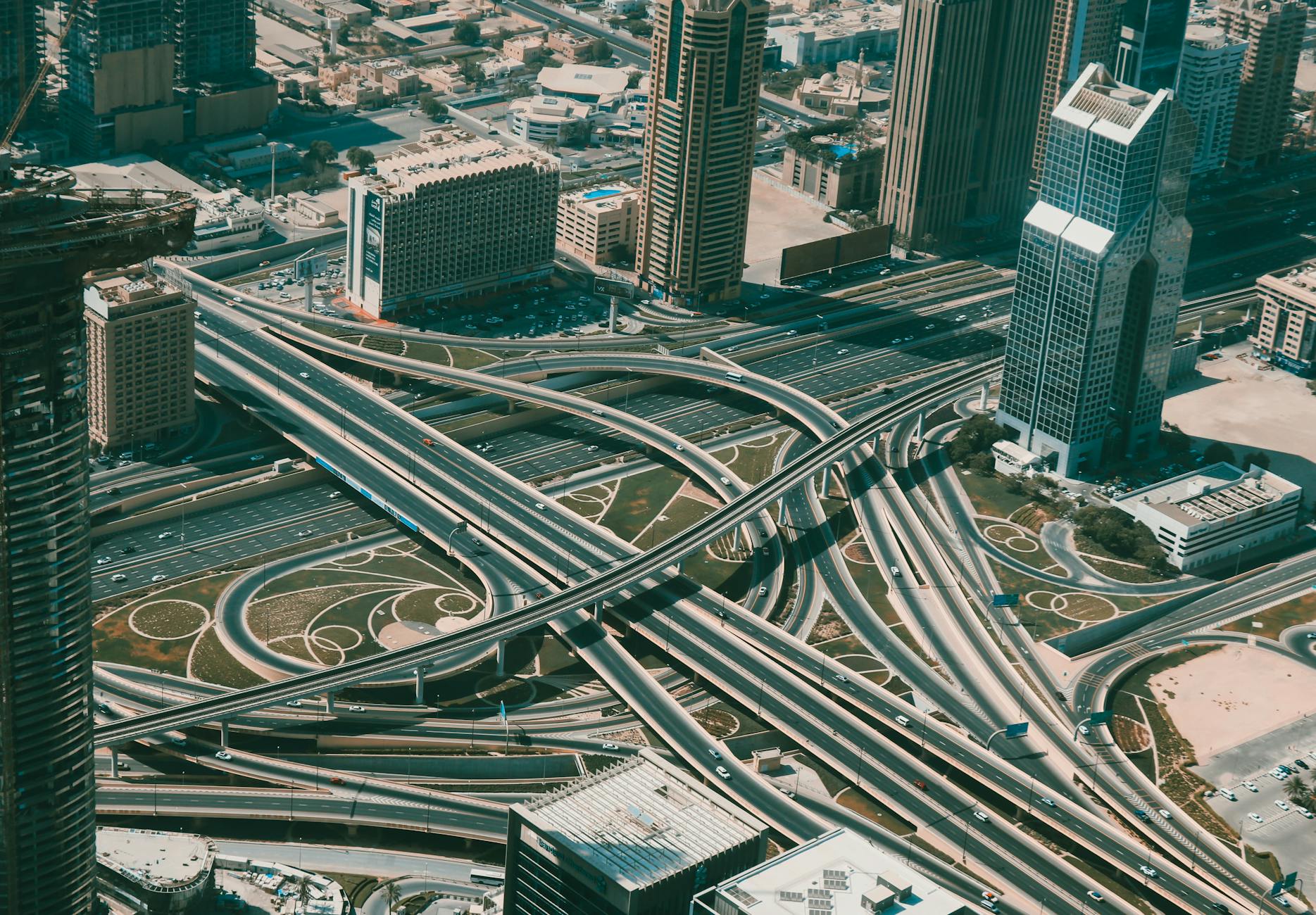 Aerial shot of Dubai's urban cityscape, featuring skyscrapers and intricate highways.