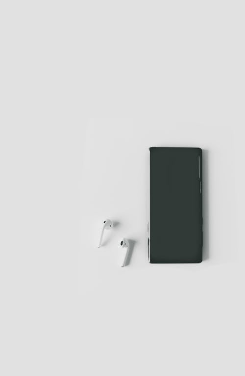A Smartphone and Wireless Earphones on a White Surface