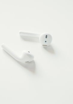 A minimalist close-up image of white wireless earbuds on a white background.
