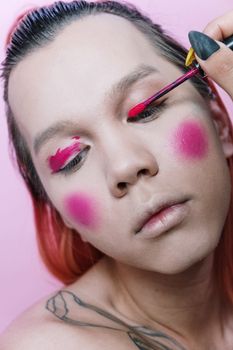 Close-up of androgynous model with bold pink makeup, showcasing artistic beauty and creativity.