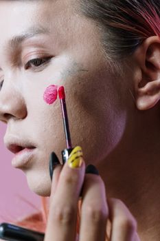 Artistic close-up of a person applying vivid pink makeup for a creative look.