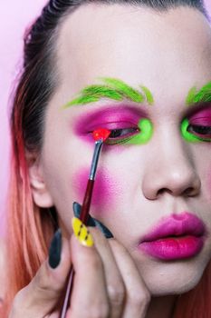 Close-up of a person with vivid artistic makeup in fluorescent colors, showcasing creativity.