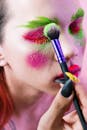 特写镜头展示了充满活力的霓虹灯化妆应用程序，用刷子进行艺术性的脸部彩绘